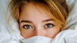 © Nikname - Close-up of a woman with freckles and brown eyes partially covered by white sheets