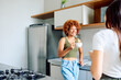 © we.bond.creations - Two happy young women friends talking and laughing while enjoying coffee together in a modern home kitchen