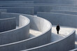© Daria - Man in a dark suit navigating through large empty modern concrete maze maze symbolizing challenge and decision making in a minimalistic architectural environment