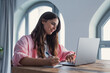 © Daniel - A focused woman sits at the table at home writing down useful information found online, such as phone numbers or addresses, organizing daily tasks and managing household responsibilities