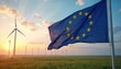 © Pete - European Union flag waves over wind turbines at sunrise. Green energy farm generates power in rural field. Sustainable development for clean future.