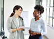 © Lumos sp - Portrait of two young business woman having a meeting or presentation and seminar standing in the office. Portrait of a young business woman talking