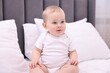© New Africa - Cute little baby sitting on bed at home