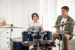 © New Africa - Little boy learning how to play drums with music teacher indoors