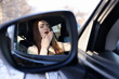 © New Africa - Woman feeling fatigue in her modern auto, view through car side mirror