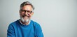 © Viktor - Mature, happy man with gray hair and beard wears glasses and blue sweatshirt. He smiles broadly at camera against plain background, looking confident and friendly, reflecting wisdom and contentment.