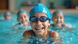 © Viktor - Young smiling boy learns swim in pool with friends. Children wear blue caps and goggles. Kids practice water sport, enjoy fun group activity and splash in water.