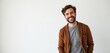 © Maryna - Young man with beard smiles broadly against white background. He wears brown cardigan over grey t-shirt, looking happy and relaxed. Casual style, friendly expression, approachable demeanor.
