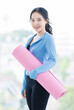 © Bangkok Click Studio - Asian young beautiful happy smiling cheerful woman active sport in sportswear standing holding yoga mat prepare exercise pilates stretching training in bright fitness gym healthy wellness lifestyle.