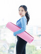 © Bangkok Click Studio - Asian young beautiful happy smiling cheerful woman active sport in sportswear standing holding yoga mat prepare exercise pilates stretching training in bright fitness gym healthy wellness lifestyle.