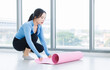 © Bangkok Click Studio - Asian young beautiful happy smiling cheerful woman active sport in sportswear sit preparing laying out a yoga mat exercise pilates stretching training in bright fitness gym healthy wellness lifestyle