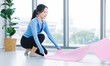 © Bangkok Click Studio - Asian young beautiful happy smiling cheerful woman active sport in sportswear sit preparing laying out a yoga mat exercise pilates stretching training in bright fitness gym healthy wellness lifestyle