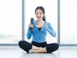 © Bangkok Click Studio - Asian young beautiful happy woman fit sporty healthy in sportswear relax rest sitting on floor holding water bottle after hard workout exercise training in bright fitness gym studio wellness lifestyle