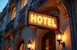 © Maryna - Glowing hotel sign on ornate building facade. Warm evening light illuminates classic architecture, suggesting luxury lodging and inviting city nights. Exterior facade detail with vintage signage.