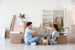 © Pixel-Shot - Happy young couple with dog giving each other high-five in rented apartment on moving day