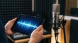 © Chanoknan - Professional audio engineer utilizing tablet waveform analysis with condenser microphone and acoustic treatment for studio recording optimization and sound quality improvement.