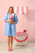 © Pixel-Shot - Young woman with ice cream figure and paper booth near pink wall. Valentine's Day celebration