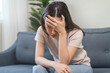 © Pormezz - Asians female in stressed expression sitting on the sofa in the house.