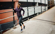 © BuyoutReese08/peopleimages.com - Running, earphones and cardio with woman in city for workout playlist, fitness challenge and health. Exercise podcast, streaming and wellness with person outdoor for runner training and athlete