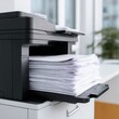 © Iryna - Modern office printer output with large stack of white paper in bright workspace