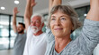 © dinatychynska - Senior woman raising arms during group fitness class, wellness center. Mature adults exercising, physical therapy, healthy aging, rehabilitation, stretching, active lifestyle, vitality.