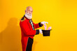 © deagreez - Elderly magician in red circus costume performs bunny trick against bright yellow background during holiday show