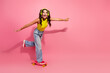 © deagreez - Young stylish girl skateboarding on pink background with headphones smiling and enjoying summer fashion