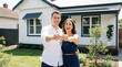 © Monktwins - New homeowners holding keys in front of a modern house. Happy young Caucasian couple on the doorstep of their first home. Real estate, home purchase, mortgage, housewarming, family joy.