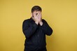 © bodnarphoto - Man covers face with hands against a yellow background during an indoor moment of stress or surprise
