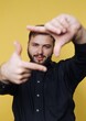 © bodnarphoto - Young man making a gesture with hands and smiling in front of a yellow background during a casual moment