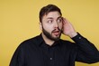 © bodnarphoto - Man listens intently while standing against a bright yellow background in a casual setting during the daytime