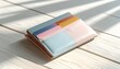 © Selvy - Pastel wallet with cards on a light wooden surface with soft shadows