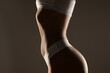 © vladimirfloyd - Side view of a woman’s torso and hips in white underwear, toned waist and abdomen, studio shot on a dark gray background
