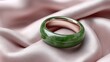 © Gulnaz - A green and gold ring sits on a pink cloth