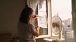 © fotogurme - Young adult woman sealing window with reflective insulation, home cooling and energy saving DIY, hot summer apartment mood with simple indoor heat protection