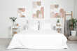 © Pixel-Shot - Interior of beautiful bedroom with comfy bed, bedside tables and pictures on white brick wall