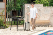 © buritora - Vacation, young Asian man walking with carry-on suitcase by the pool at a resort