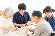 © buritora - Elderly people and male and female caregivers doing origami in a group home or nursing home