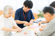 © buritora - Elderly people and male and female caregivers doing origami in a group home or nursing home