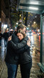 © Eliane - A poignant and emotional candid moment of a couple embracing tightly on a rainy city street at night, symbolizing support, comfort, and deep affection during a difficult time.