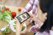 © sofiko14 - A person is using a smartphone to photograph a plate of fresh salad, capturing a healthy meal