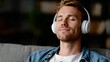 © Jane_S - Young caucasian male relaxing with headphones at home