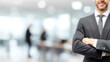 © CStock - A confident businessman stands with arms crossed in a modern office setting, conveying professionalism and success.