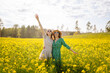 © maxbelchenko - Happy girlfriends in dresses are having fun in a yellow field in the sun's rays. Two young women are strolling, spending time together outdoors. Concepts of friendship and fashion.