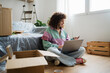 © TrueShot | Westend61 - Woman making online payment with laptop at home surrounded by boxes