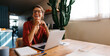 © (JLco) Julia Amaral - Woman smiling at laptop in bright kitchen