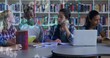 © vectorfusionart - Sitting students in casual clothing discussing schoolwork at school library, with laptop and books