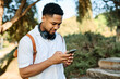 © Lumos sp - Young man enjoys sunny day while using smartphone and listening to music with earphones in urban setting, highlighting his joy and connection to the world around him