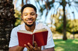 © Lumos sp - Young man student businessman enjoys sunny day while reading a book in park, highlighting his joy and connection to the world around him