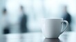 © Firadoaw - Calm professional office scene with sharp focus on a white coffee mug on desk, colleagues softly blurred in background